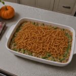 Green bean casserole topped with golden fried onions in a white baking dish