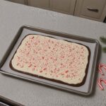 Slab of peppermint bark topped with crushed candy canes on parchment